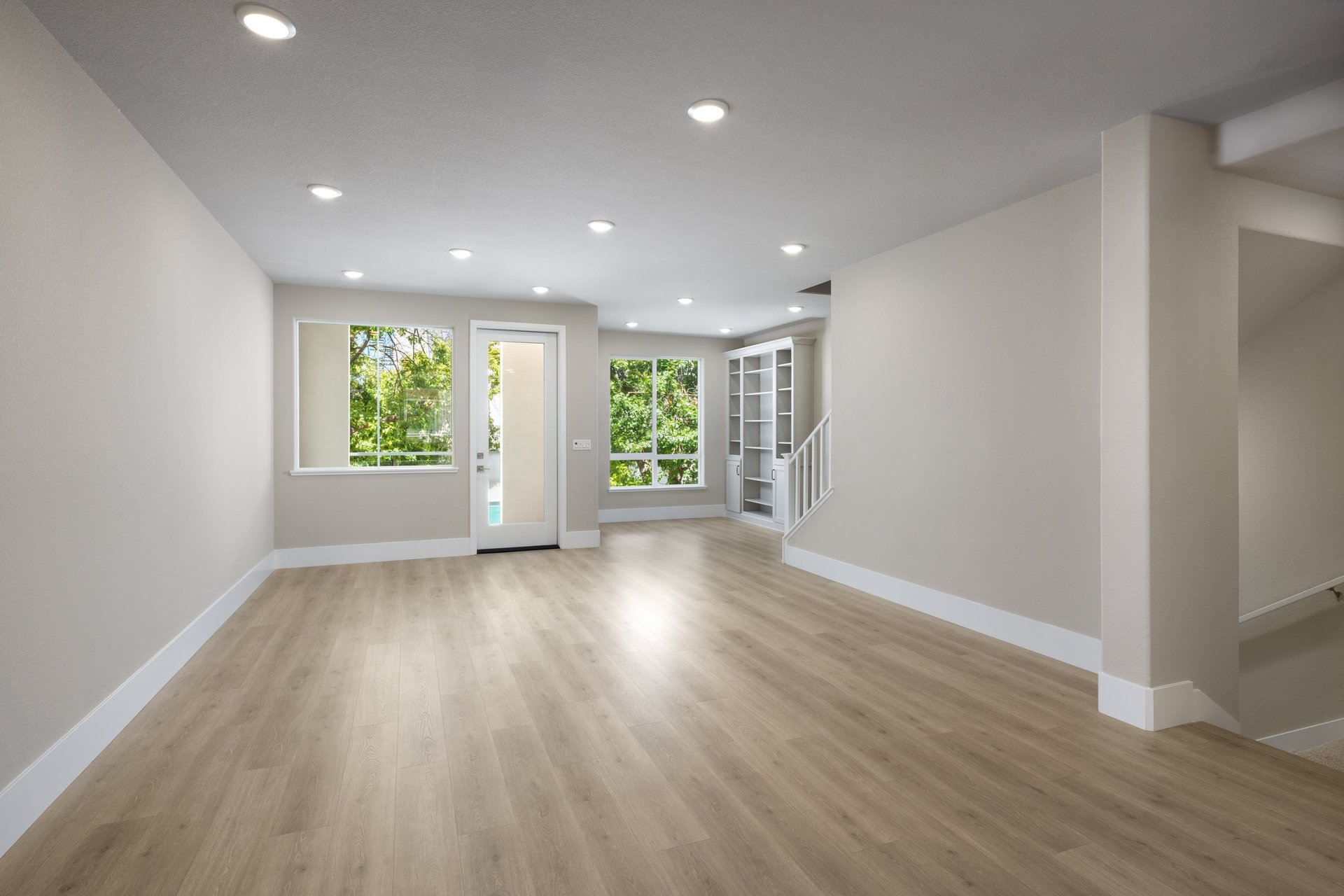great room with wood floors, light tan walls, built in cabinets, and french door leading to covered deck