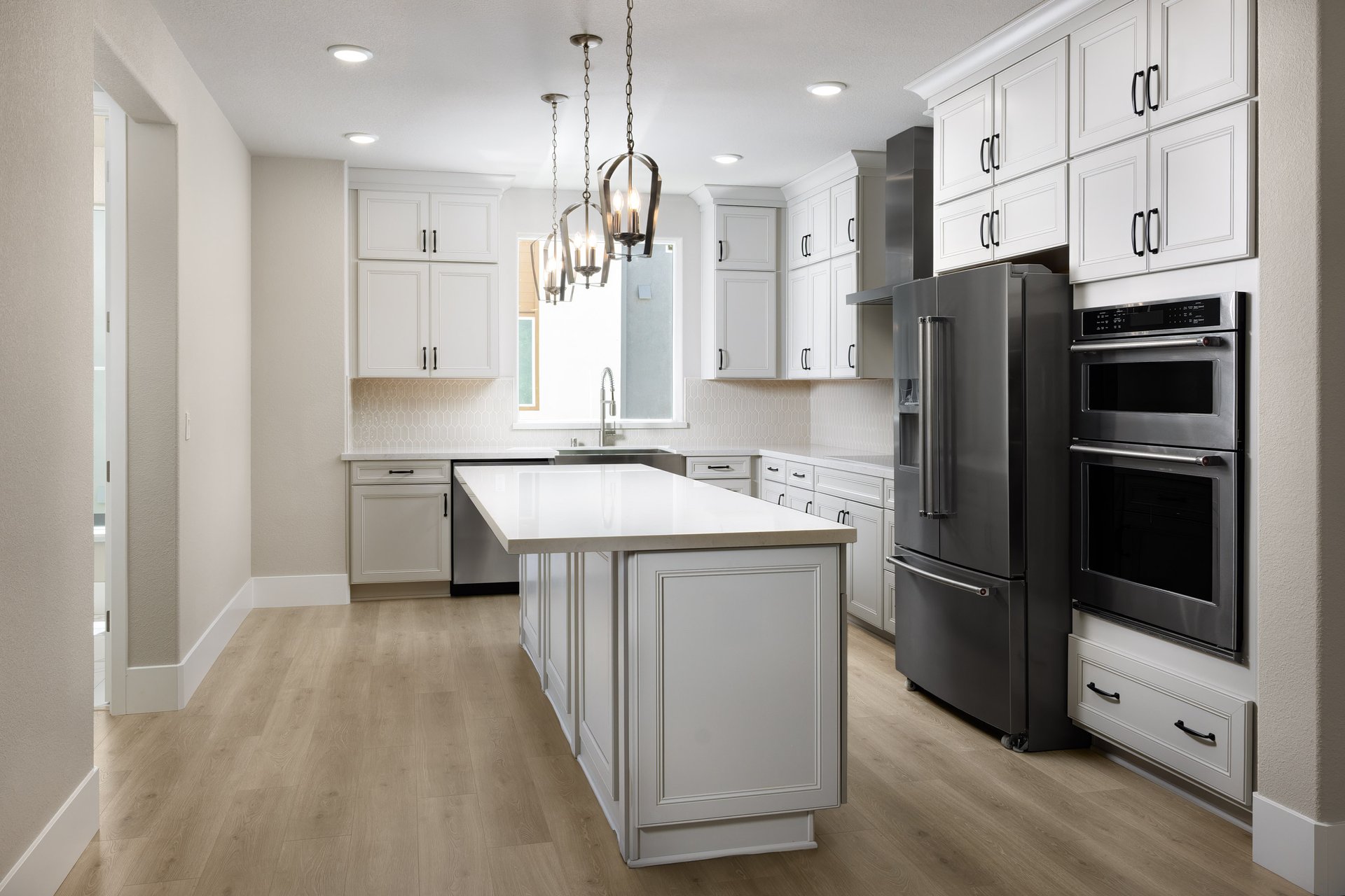 kitchen with white ceiling height cabinets, wood floors, island, and window above sink