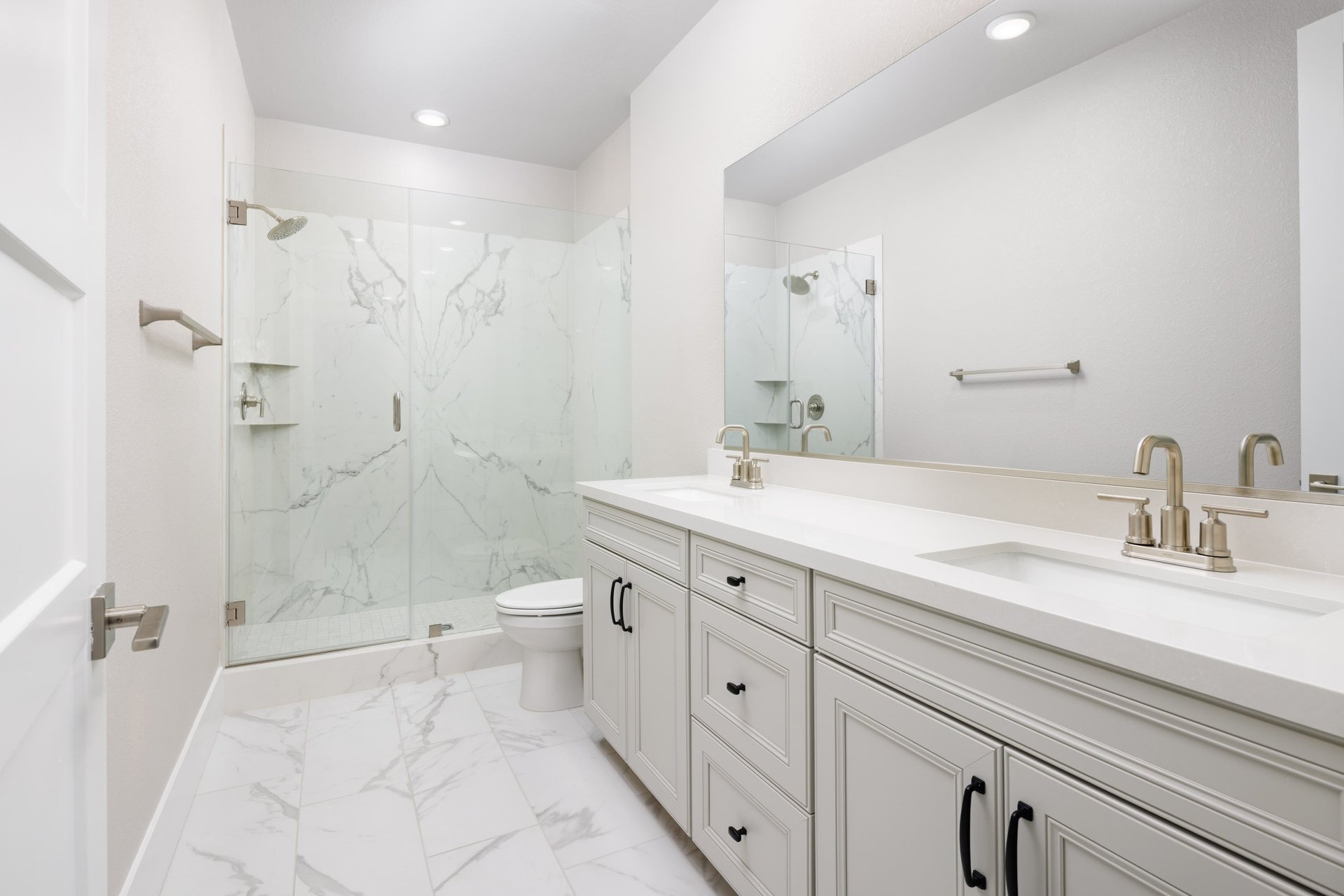 bathroom with white cabinets & counters, two sinks, and large walk-in shower with glass enclosure