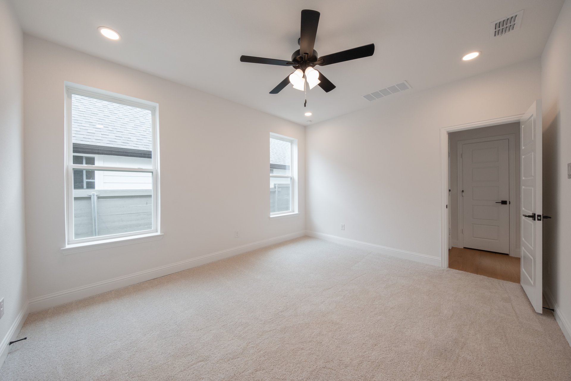 large primary bedroom with carpet and windows