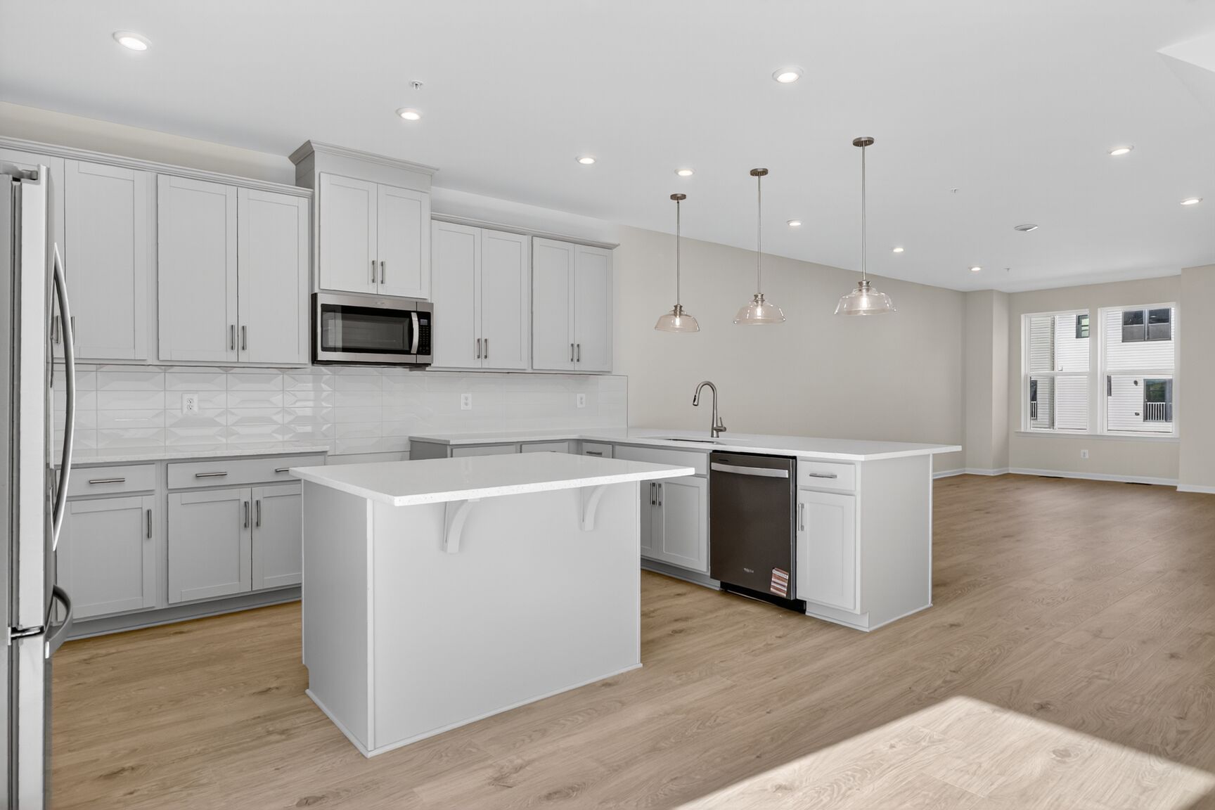 rear kitchen with white cabinetry and great room
