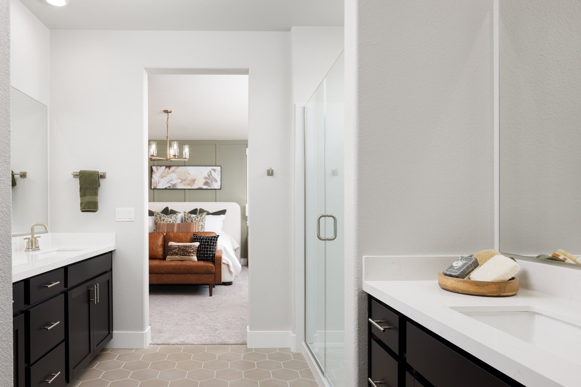 bathroom with black cabinets, white counters, dual separate vanities, shower, and tan tile floor