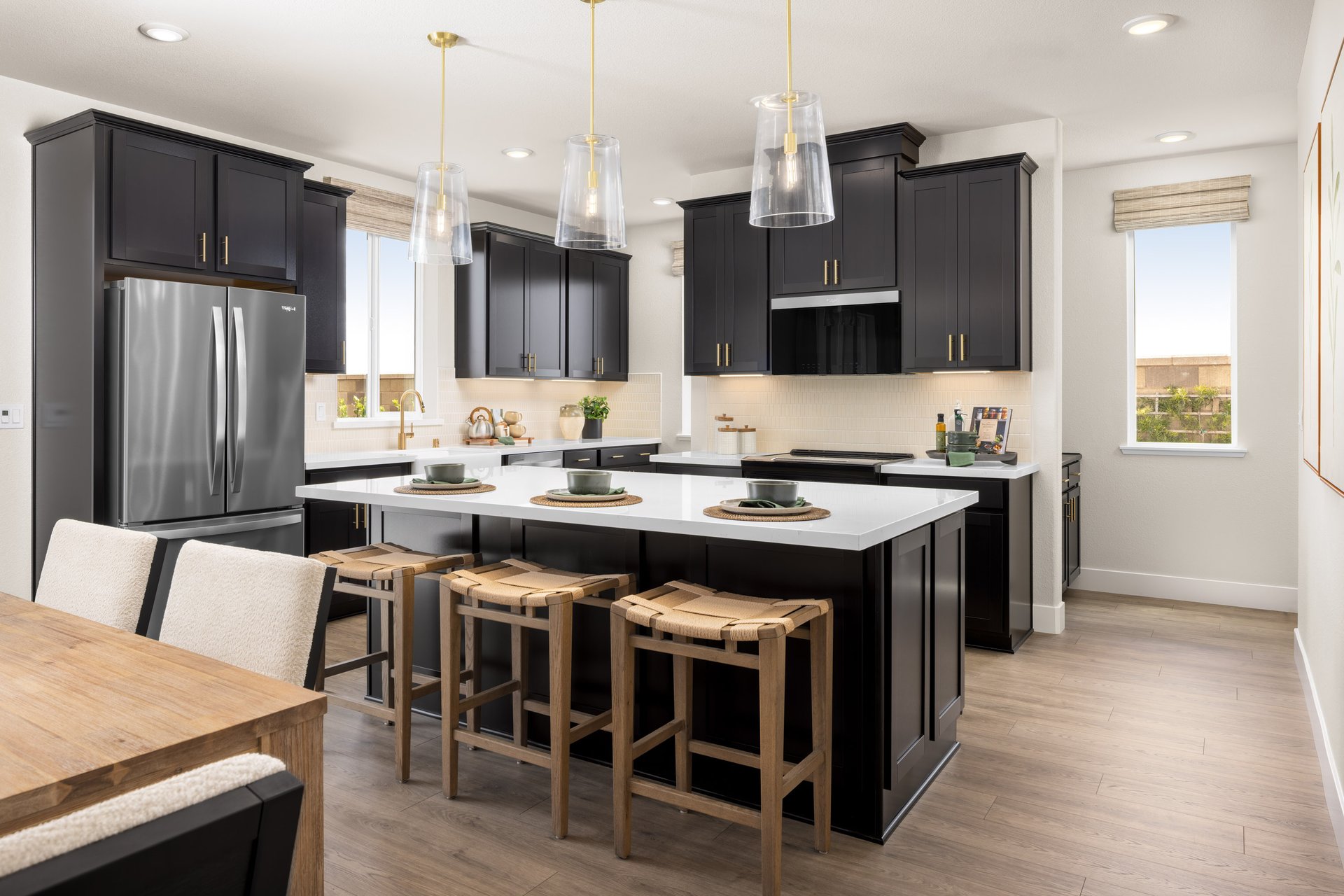 kitchen with black cabinets, white counters, wood floors, and three glass pendant lights above island