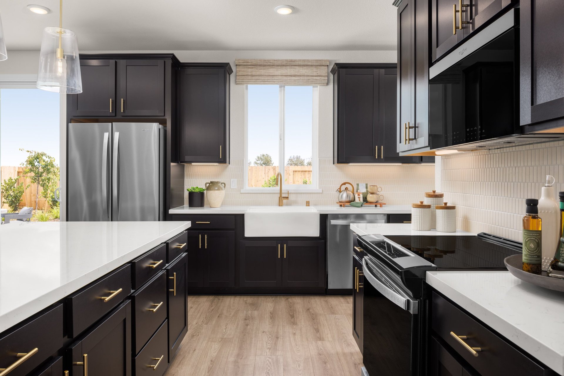 kitchen with wood floors, black cabinets, white counters, island, and window above sink