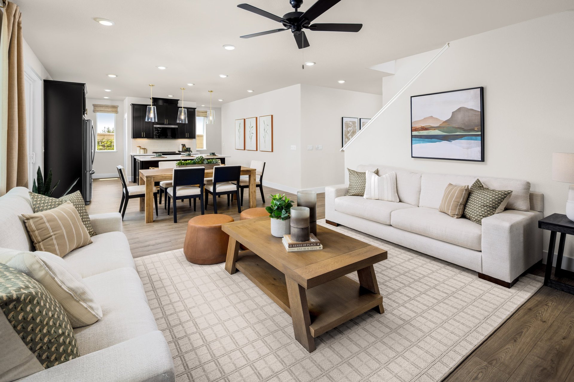 great room with two white sofas, wood coffee table, and black ceiling fan