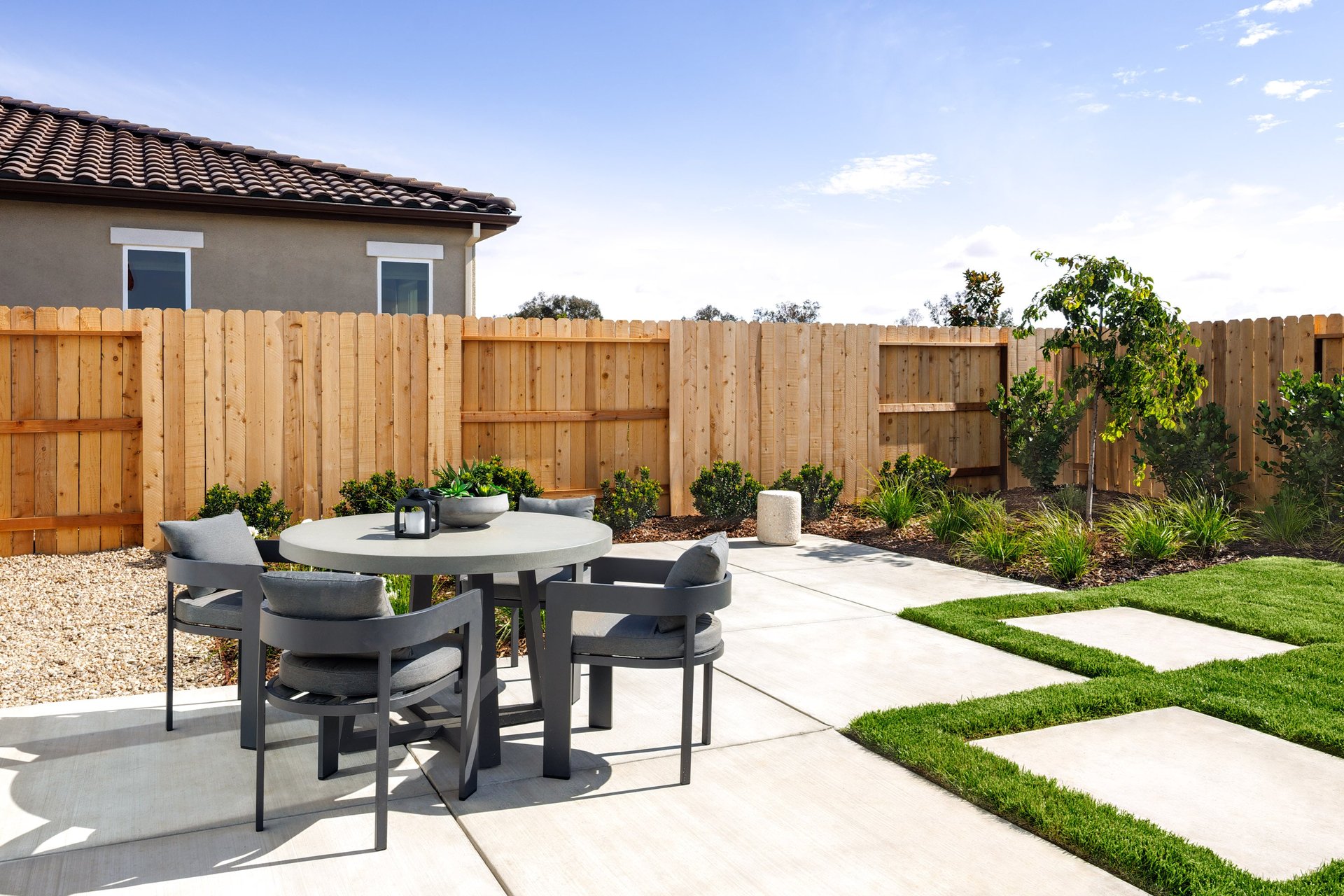 backyard with grass, and concrete patio with round dining table and four gray chairs