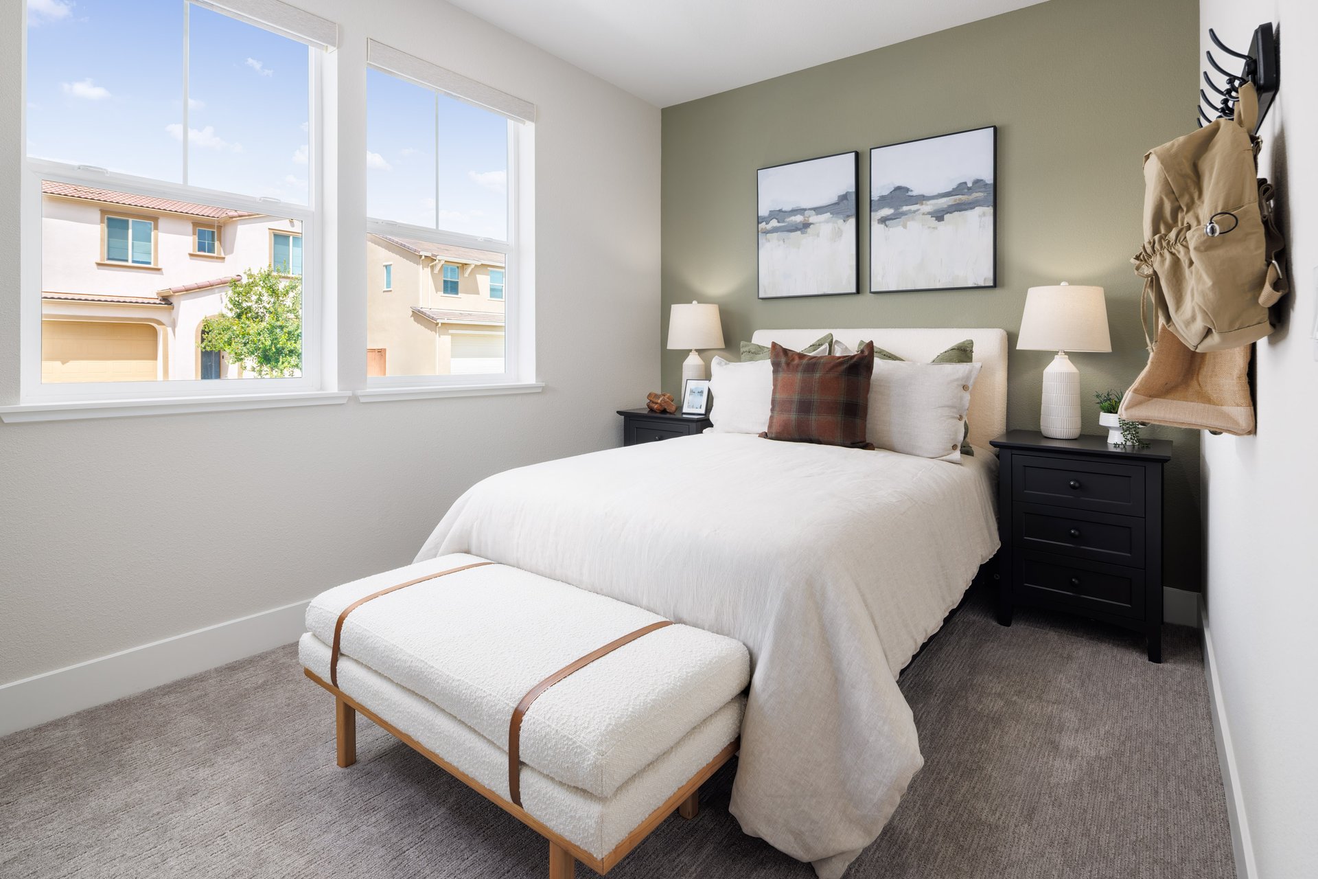 bedroom with gray carpet, green accent wall behind white bed, and two windows