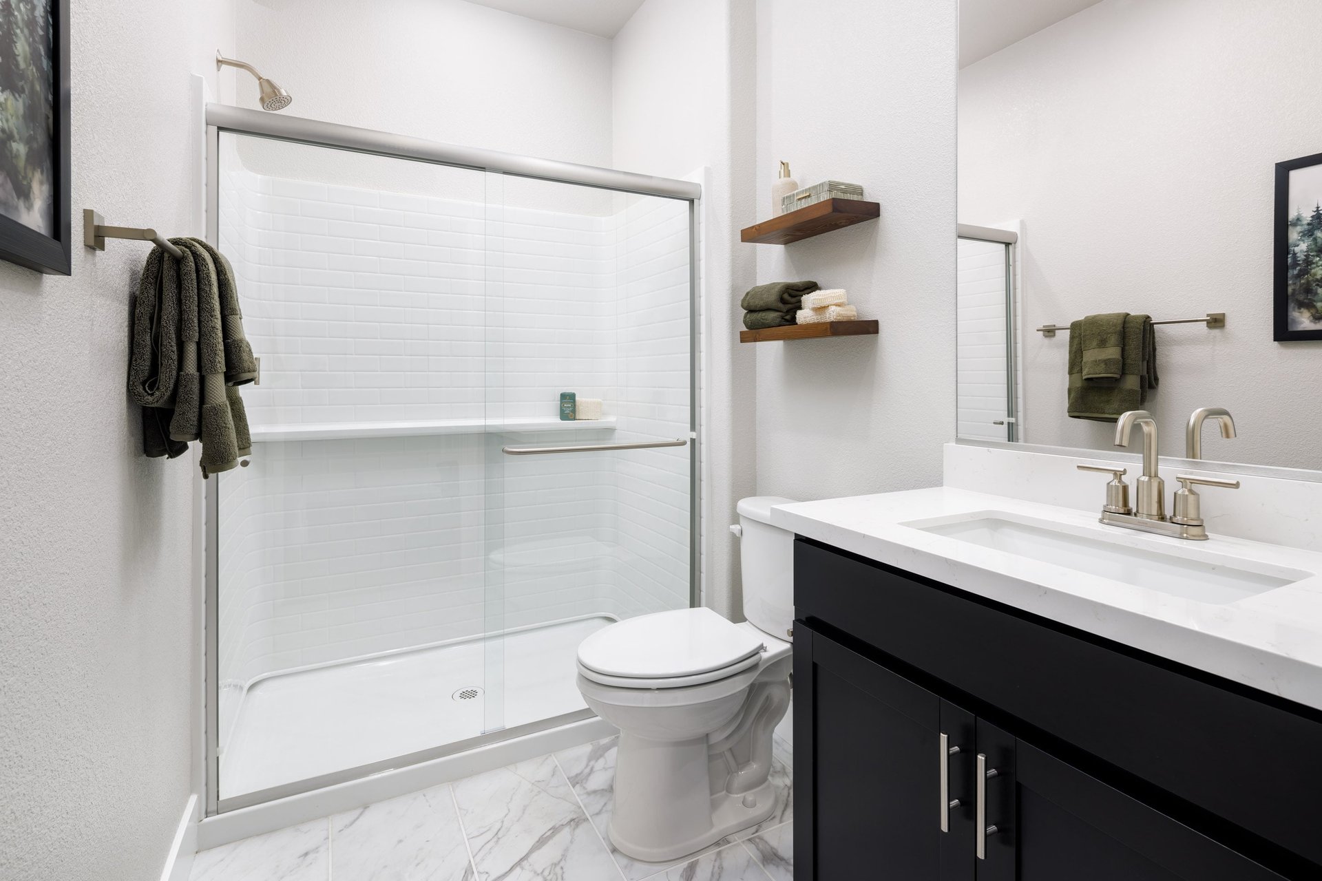 bathroom with black cabinets, white counters, two wood shelves, and walk-in shower