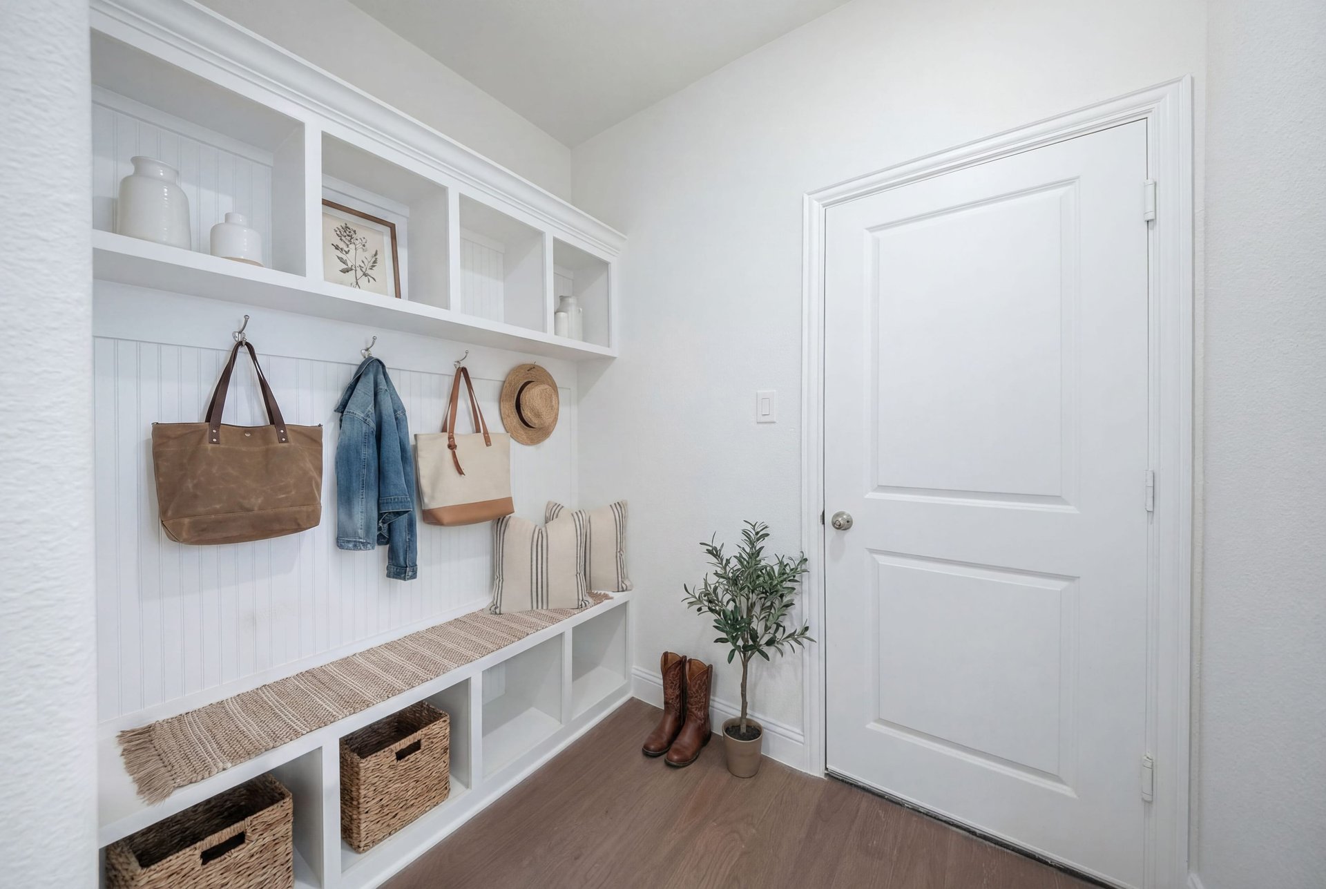 mudroom with wood floors and white shelves with bench