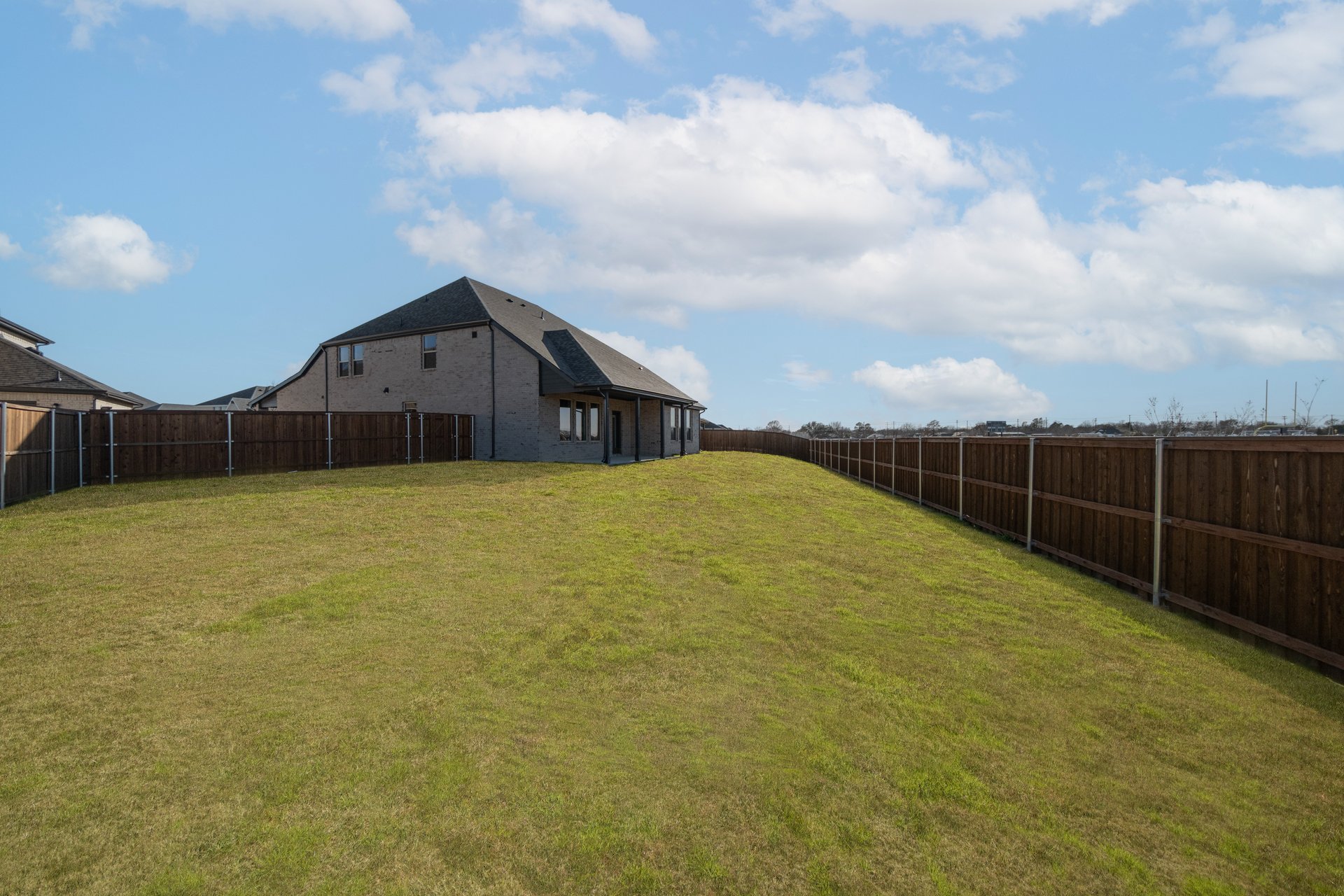 large backyard with grass and covered patio