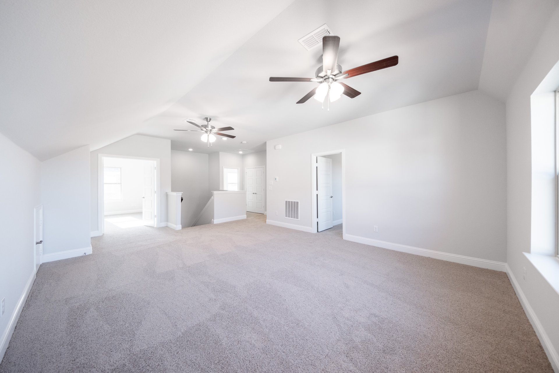 open loft with carpet and ceiling fan