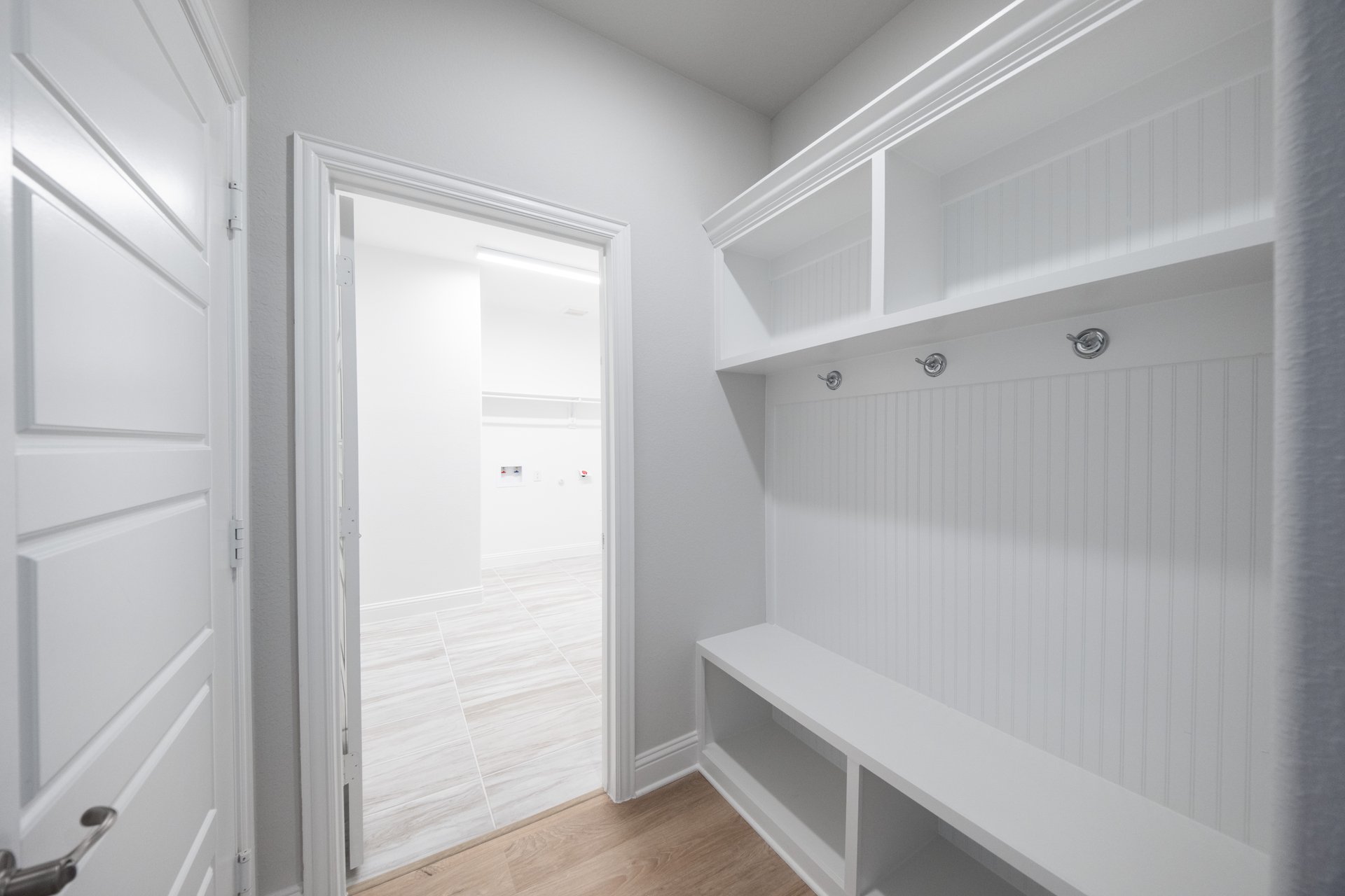 mudroom with wood floors and white shelves with bench