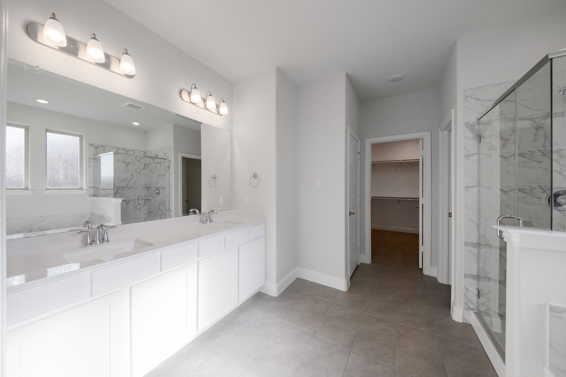 primary bathroom with white cabinets and tile floors 