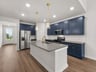 Kitchen with brown flooring, navy blue cabinents and quartz countertop