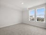 secondary bedroom with dual windows, carpet and pendant lighting 