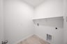 laundry room with tile floors and white shelf