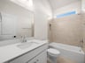secondary bathroom with sink, soaking tub and brown tile
