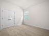 secondary bedroom with carpet, window and double doors to closet