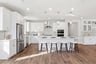 kitchen with white cabinets & counters, wood floors, three brushed nickel pendant lights above island, and four espresso barstools