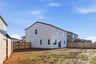 unfinished backyard of two-story white home with wood fence