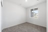 bedroom with tan carpet, white walls, and window