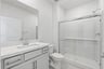 bathroom with white cabinets & counter, chrome faucet, and walk-in shower