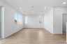 great room with light wood floors, white walls, three windows, and recessed ceiling lights