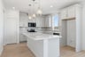 kitchen with white cabinets, white quartz counters, light wood floors, and window above sink