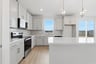 kitchen with white cabinets & counters, light wood floors, window, and two silver light pendants above island