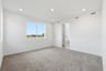 bedroom with tan carpet, white walls, window, and view of attached bathroom