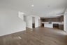 great room with wood floors, white walls, and view of kitchen with brown cabinets