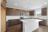 kitchen with brown cabinets, wood floors, white quartz counters, island, and window over sink