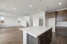 kitchen with brown cabinets, white counters, island, walk-in pantry, and wood floors