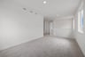 loft with tan carpet, white walls, windows, and view of stair rail leading down