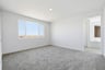 bedroom with tan carpet, large window, white walls, and view of attached bathroom