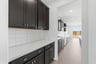 butler's pantry with espresso upper and lower cabinets, white quartz counters, and wood floors