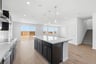 kitchen with wood floors, espresso cabinets, white counters, and three gold pendant lights above island