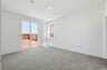 bedroom with tan carpet, white walls, window, and sliding glass door to the backyard