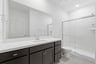 bathroom with espresso cabinets, white quartz counters, and walk-in shower