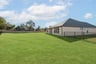 large backyard with wrought iron fence, grass, and covered patio