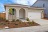 front exterior of tan & white single-story home with two arches at front porch 