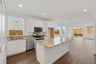 kitchen with white cabinets, granite counters, island, wood floors, and window above sink