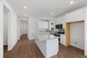 kitchen with wood floors, white cabinets, granite counters, and view of entry foyer