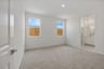 bedroom with light tan carpet, two windows, and view of attached bathroom