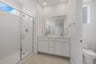 bathroom with white cabinets & counters, two sinks, and window above large walk-in shower with glass enclosure