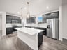 kitchen with black cabinets, quartz countertops & pendant lighting