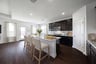 open kitchen with black cabinets and hardwood flooring