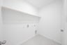 laundry room with tile floors and white shelf