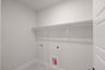 laundry room with tile floors and white shelf