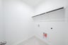 laundry room with tile floors and white shelf